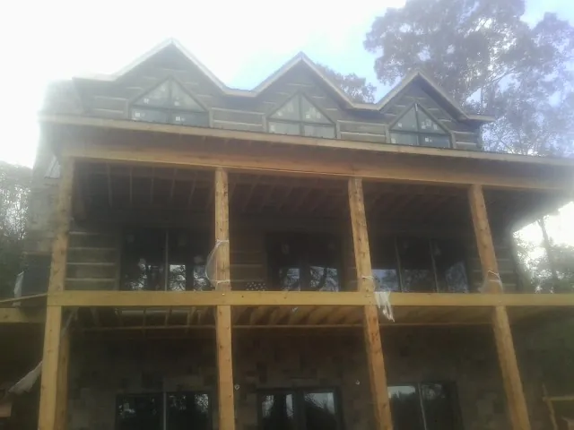 Dormers and porch framing on a large log home under construction — Roof Coating work by our crew in Carmel